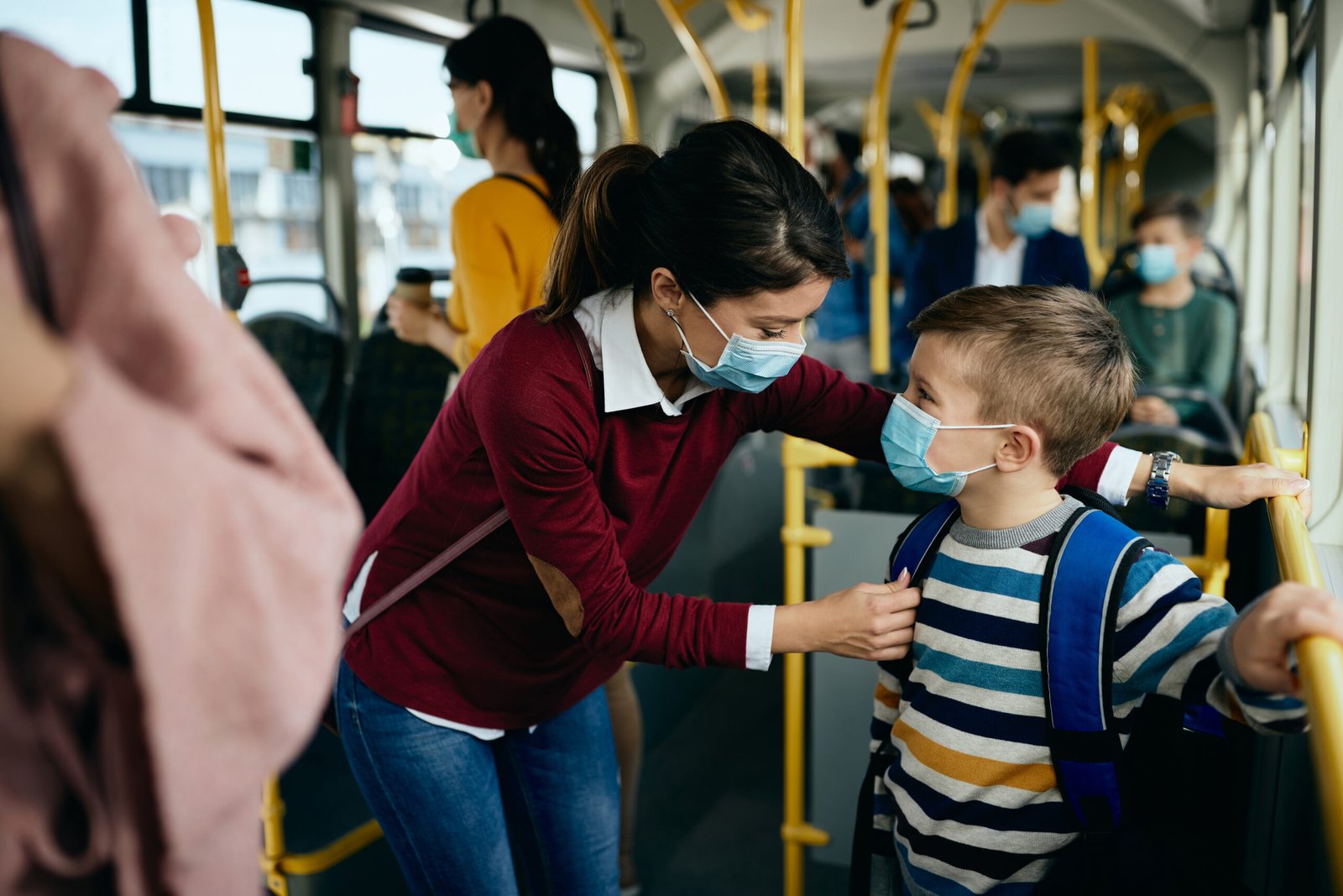 Happy mother and son wearing face masks while commuting to schoo